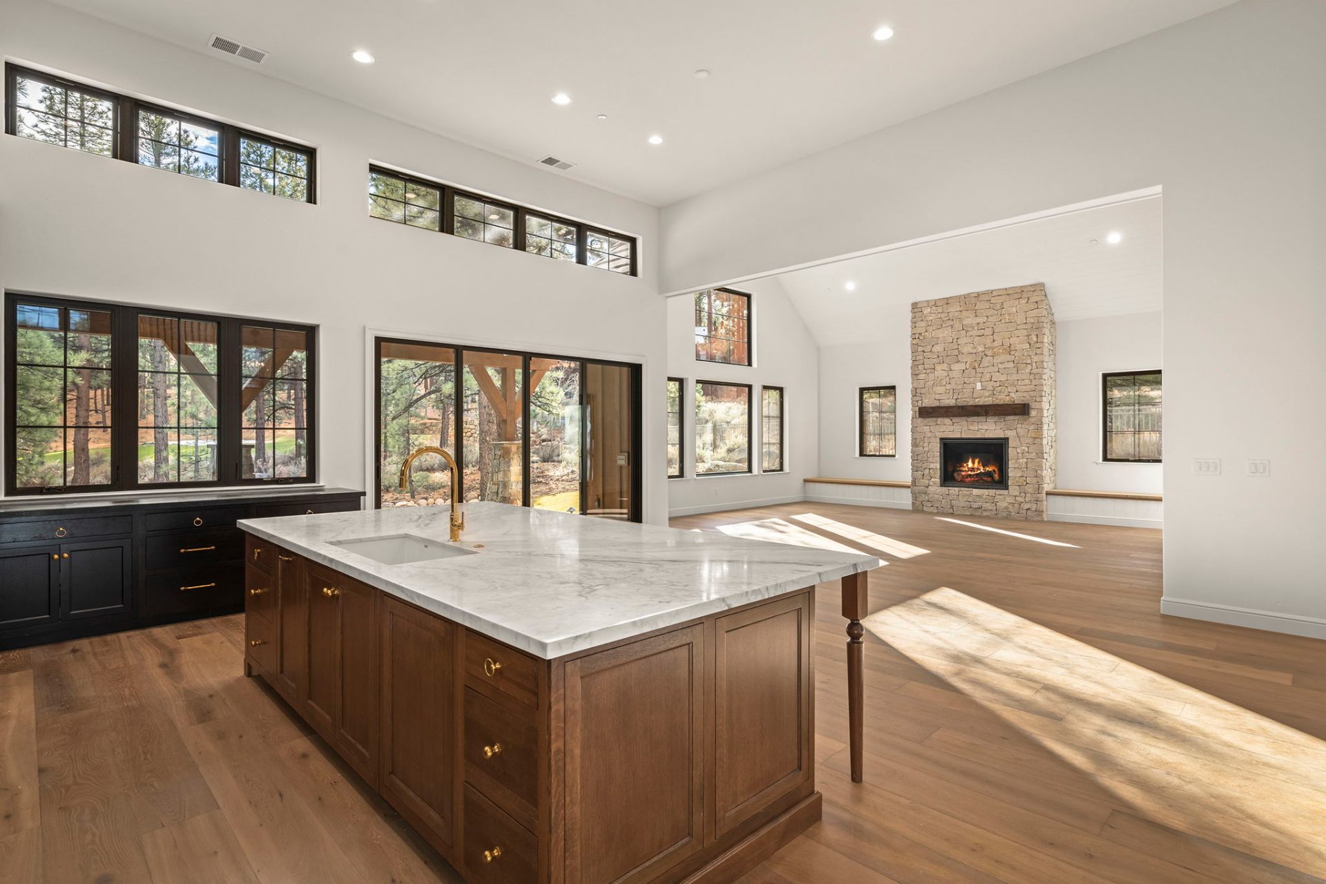 Great room and kitchen with vaulted ceilings, marble island, and stone fireplace