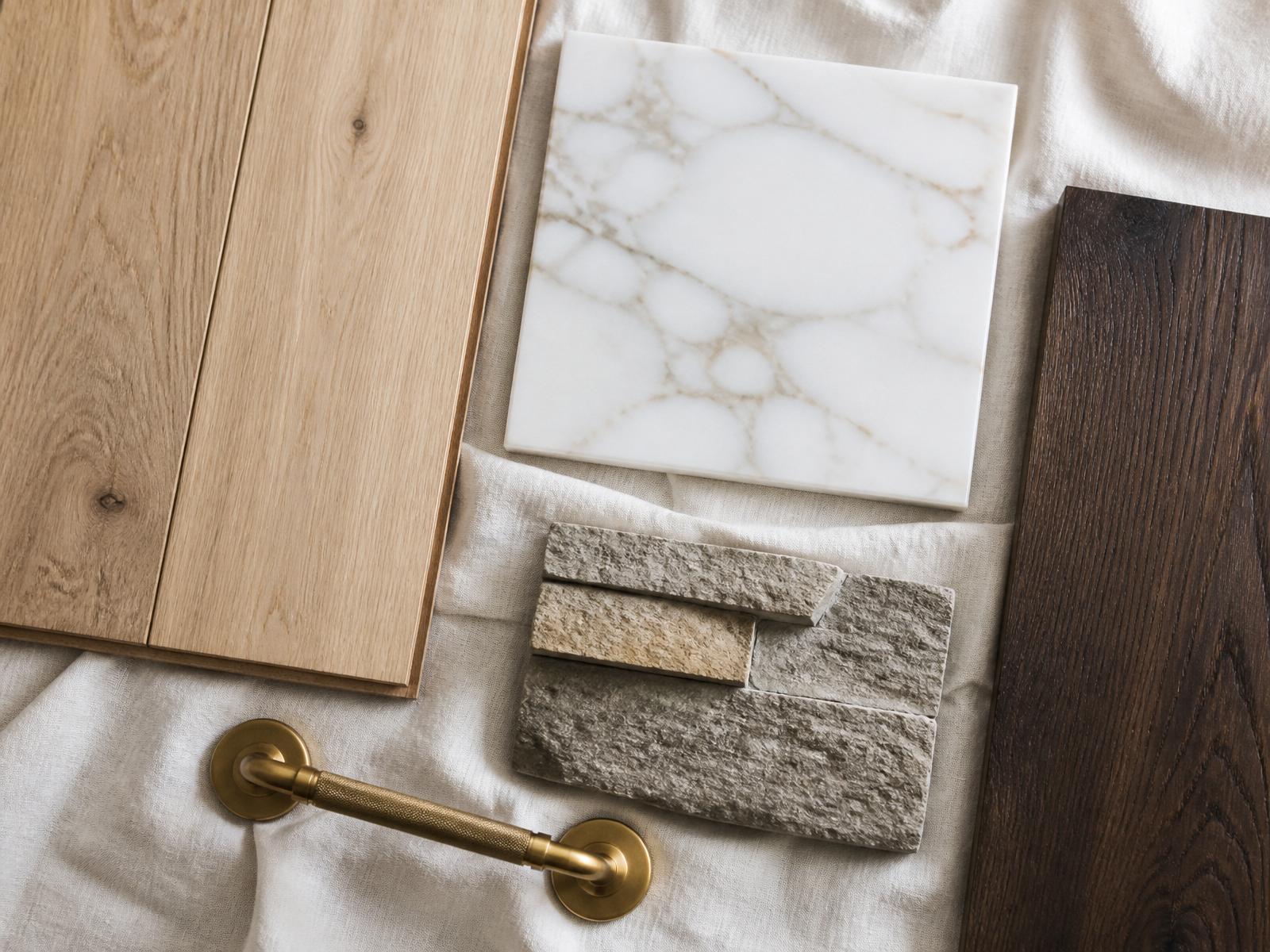 Material selection board with white oak flooring, marble mosaics, onyx tile, quartz slabs, carpet, and paint samples