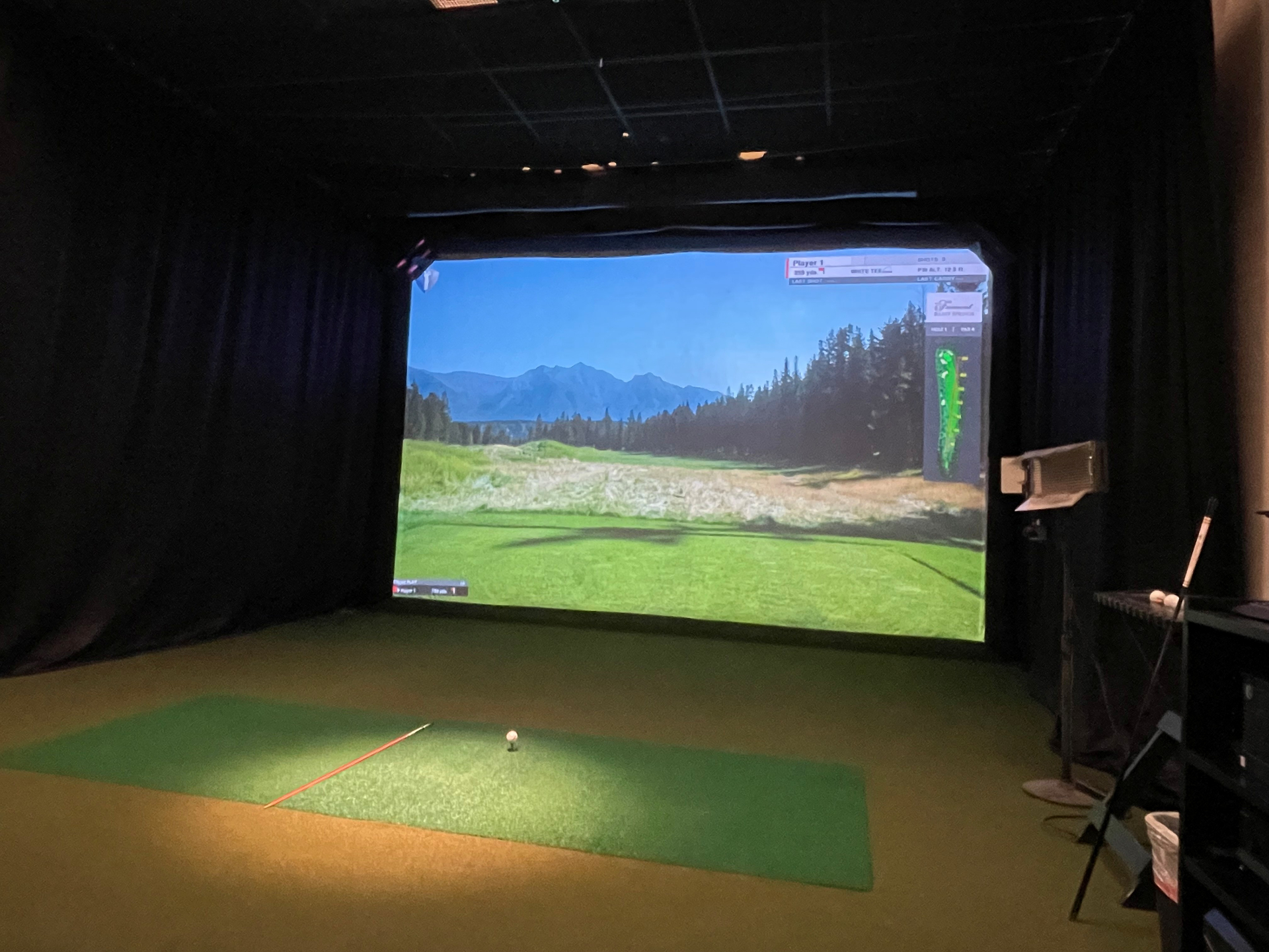 Private indoor golf simulator with high-definition projection screen and hitting mat