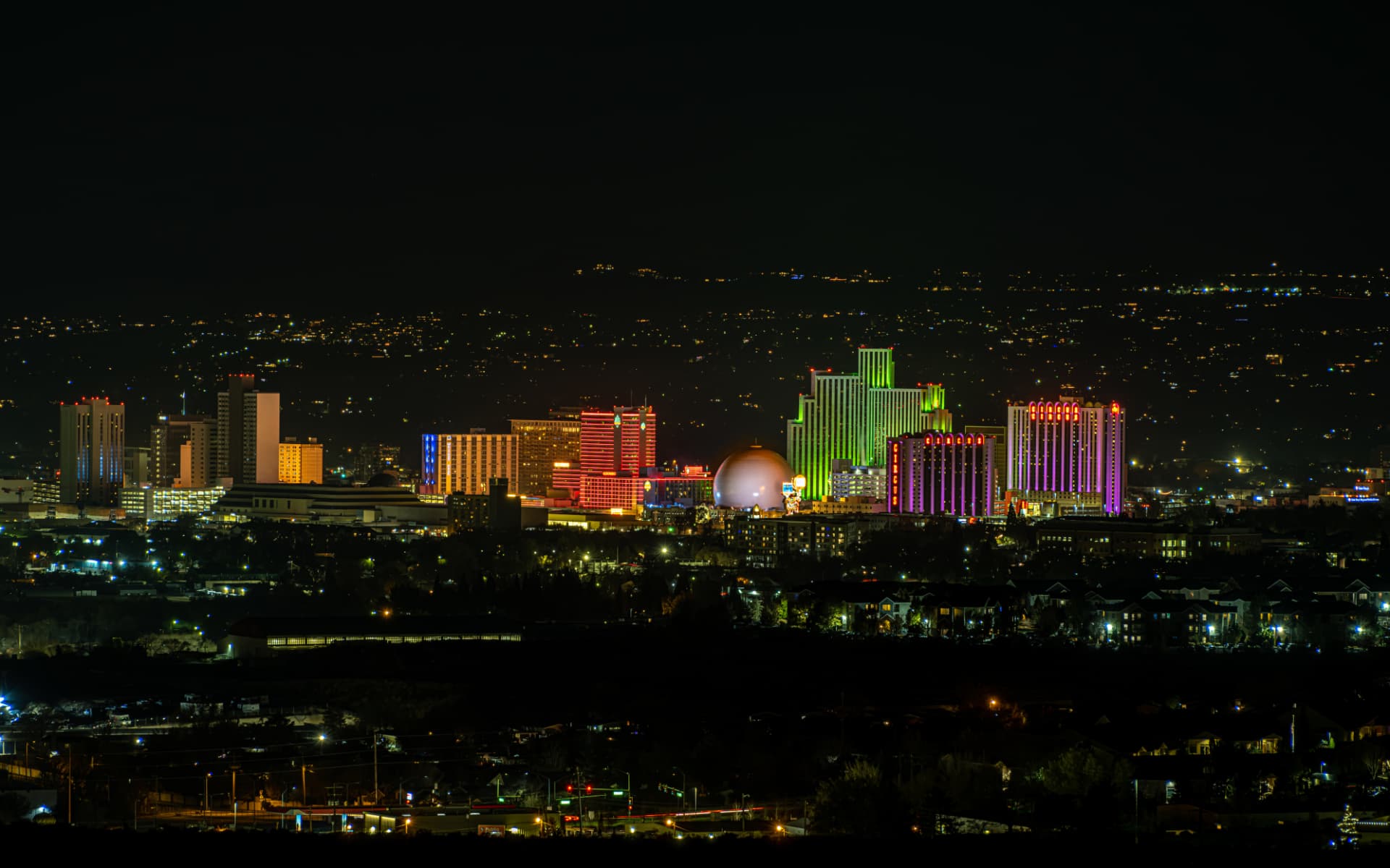 The illuminated Reno skyline glowing at night across the valley