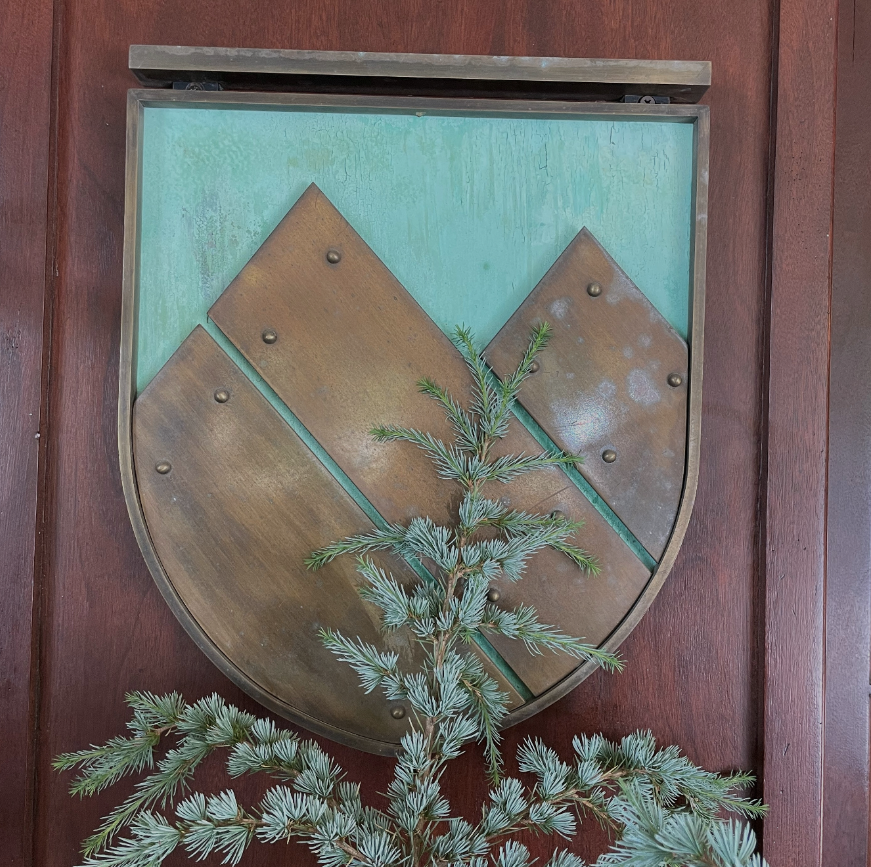 Patinated copper Montreux shield mounted on a mahogany entry door