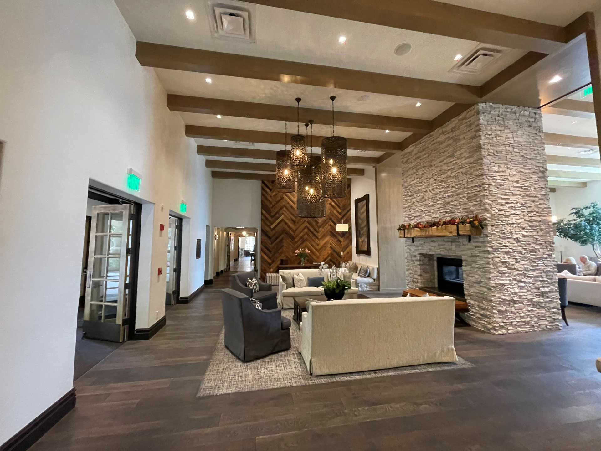 Grand clubhouse lobby with vaulted beamed ceilings, stacked-stone fireplace, and herringbone wood accent wall