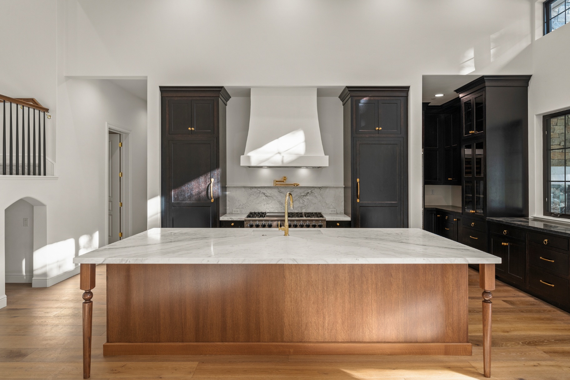 Chef's kitchen with marble island, walnut base, and blackened cabinetry